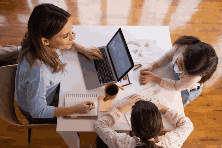 Three people collaborating around a table with a laptop.