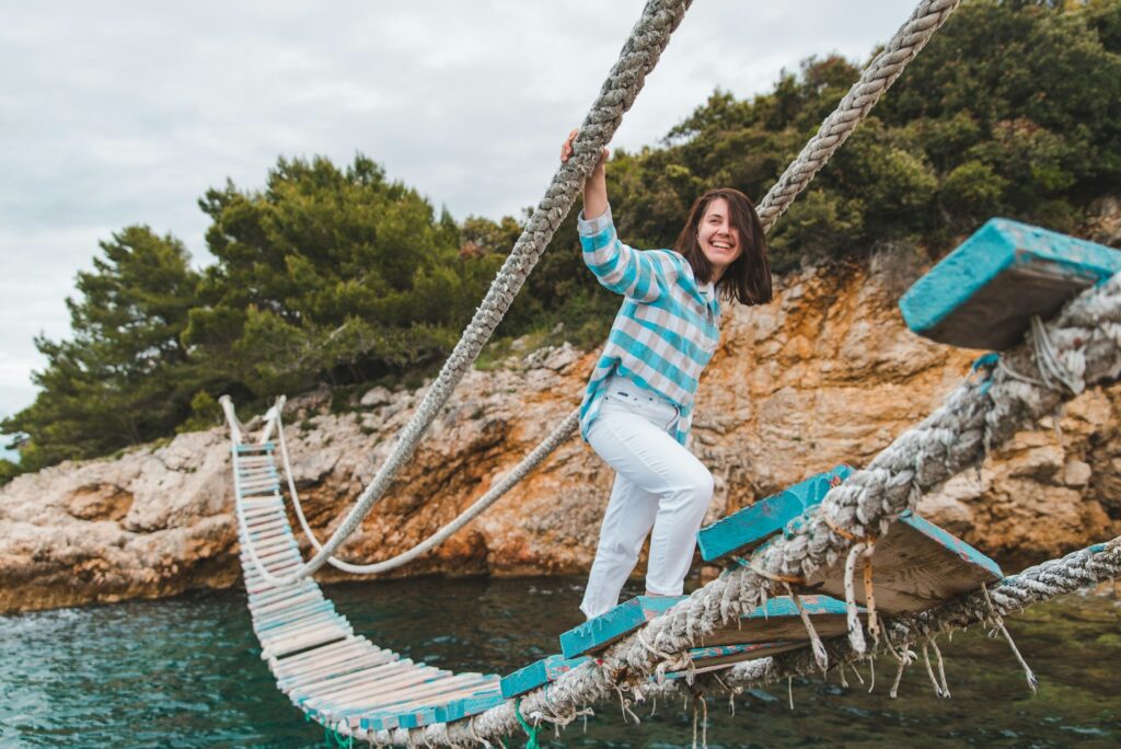 woman crossing suspension bridge sea on background